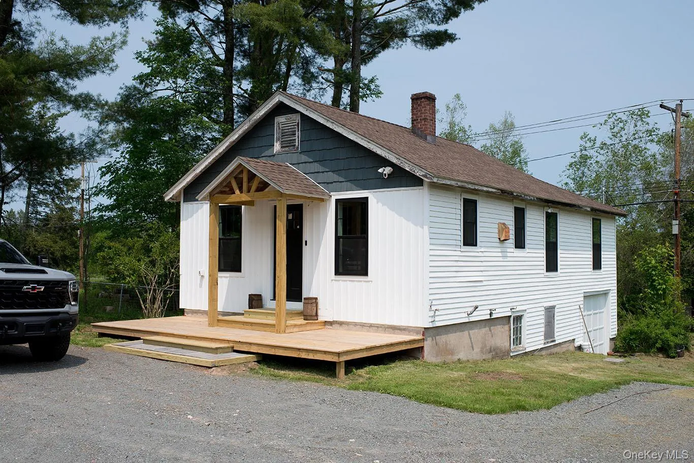 View of front of property featuring a shingled roof, a chimney, a deck, and board and batten siding View of front of property featuring a shingled roof, a chimney, a deck, and board and batten siding