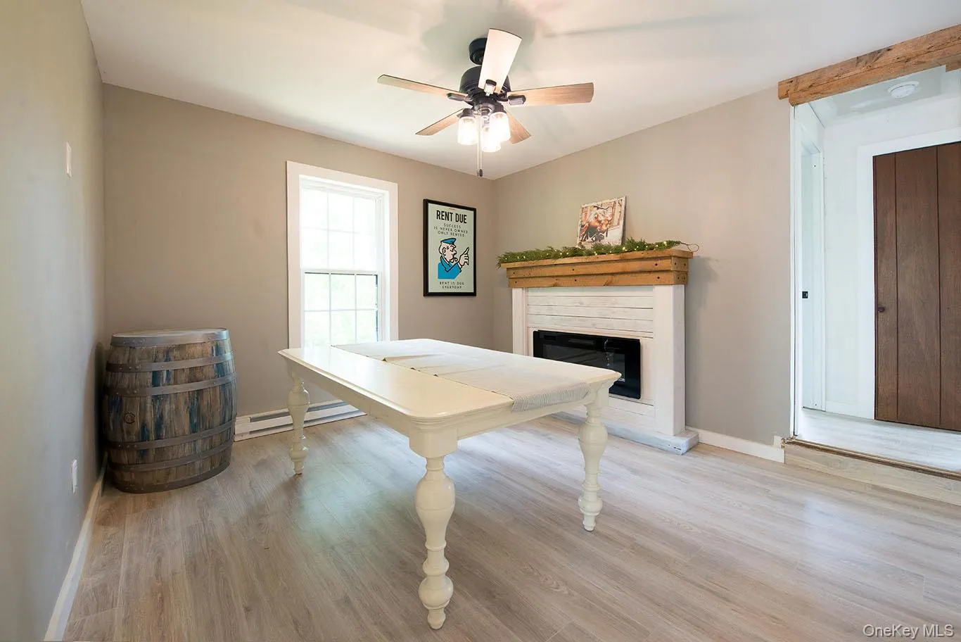 Playroom featuring light wood-style flooring, a glass covered fireplace, a baseboard heating unit, and ceiling fan Playroom featuring light wood-style flooring, a glass covered fireplace, a baseboard heating unit, and ceiling fan