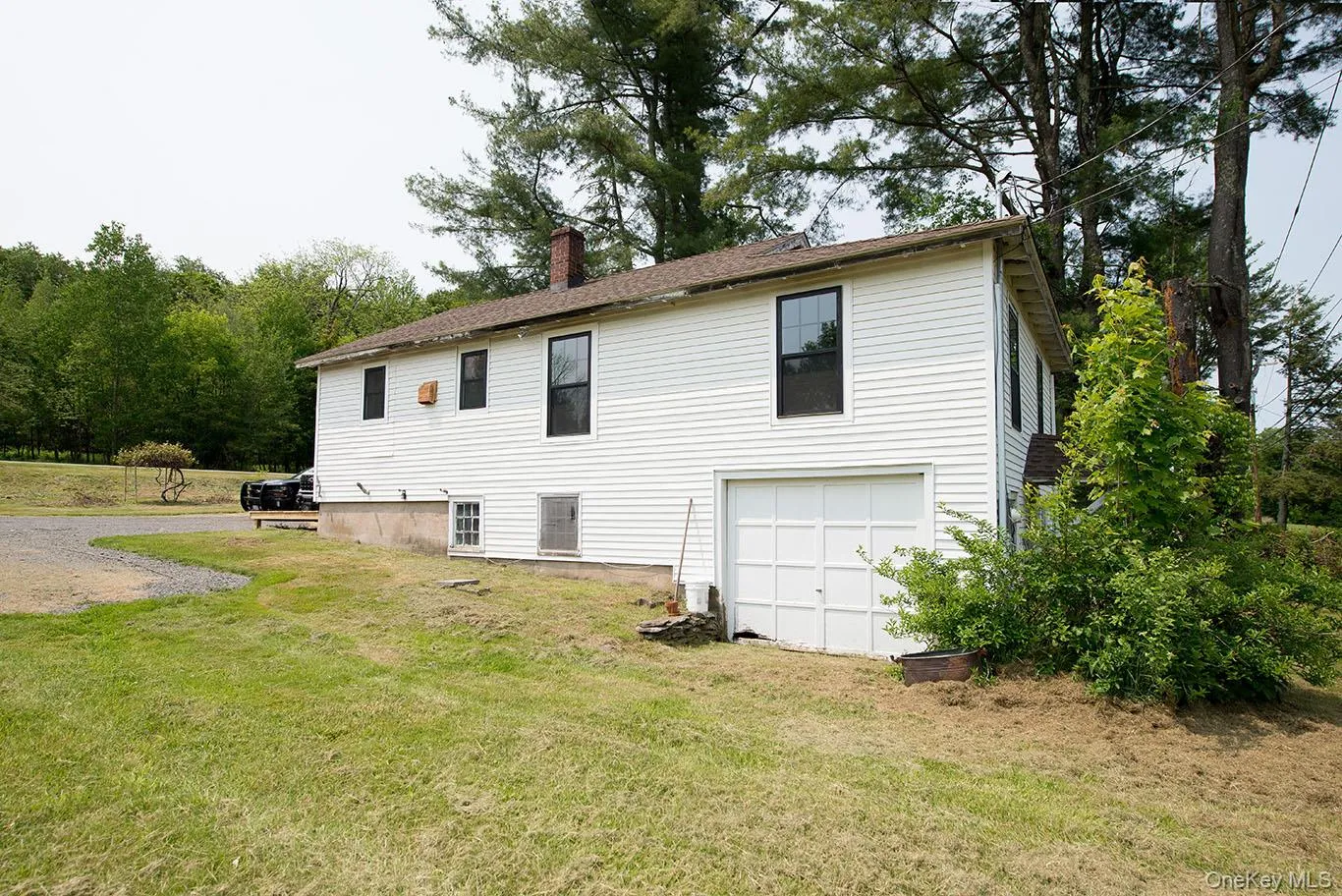 Back of property featuring a yard, a chimney, and an attached garage Back of property featuring a yard, a chimney, and an attached garage