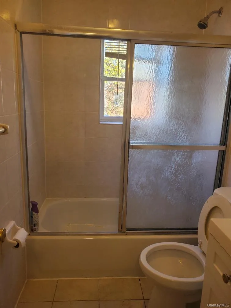 Full bathroom featuring enclosed tub / shower combo, tile patterned flooring, and vanity Full bathroom featuring enclosed tub / shower combo, tile patterned flooring, and vanity