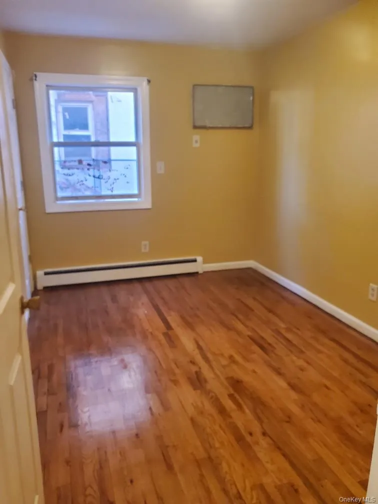 Unfurnished room featuring a baseboard radiator and dark wood-style floors Unfurnished room featuring a baseboard radiator and dark wood-style floors