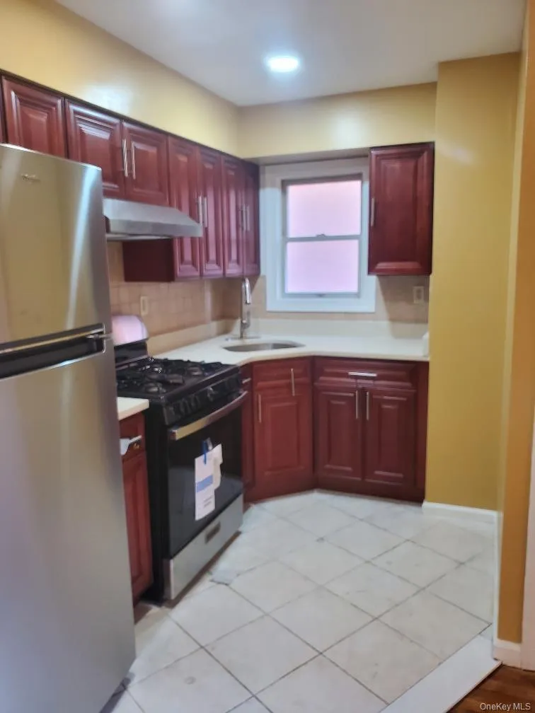 Kitchen with stainless steel appliances, reddish brown cabinets, and light countertops Kitchen with stainless steel appliances, reddish brown cabinets, and light countertops