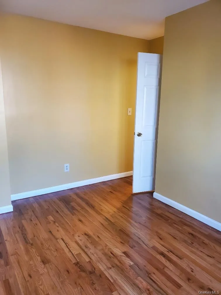 Unfurnished room with baseboards and dark wood-style floors Unfurnished room with baseboards and dark wood-style floors