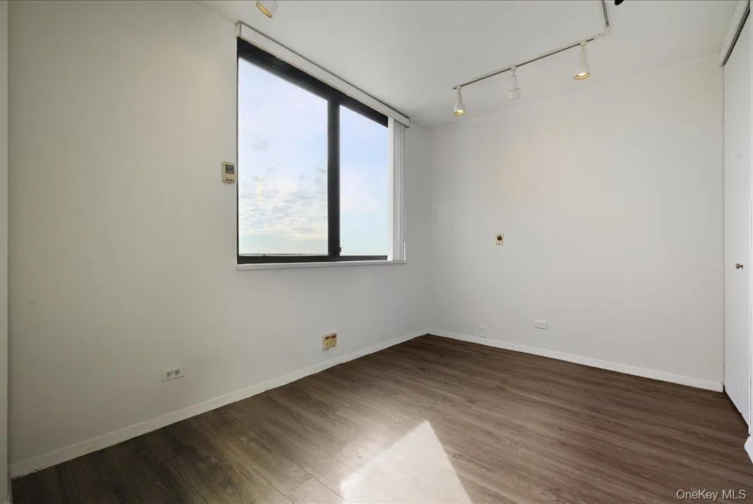 Empty room featuring track lighting and dark wood-style flooring Empty room featuring track lighting and dark wood-style flooring