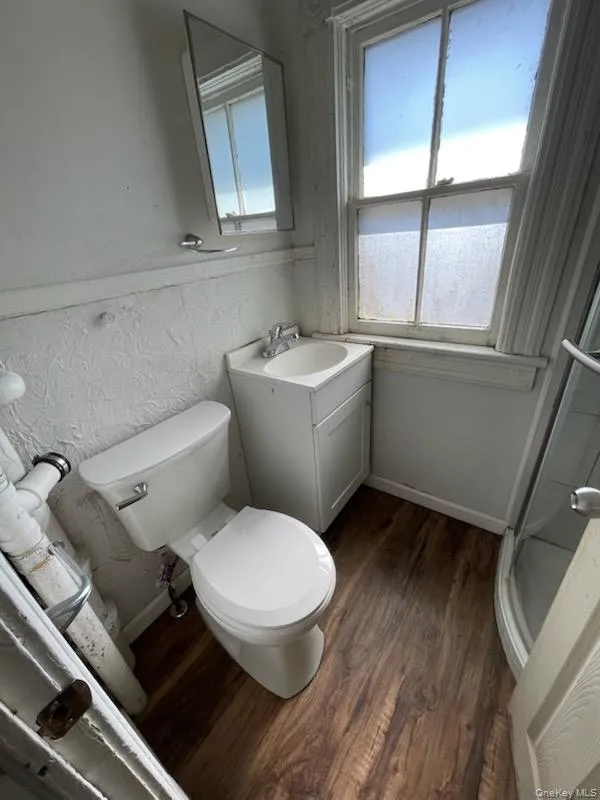 Full bath with vanity, wood finished floors, baseboards, a shower stall, and toilet Full bath with vanity, wood finished floors, baseboards, a shower stall, and toilet