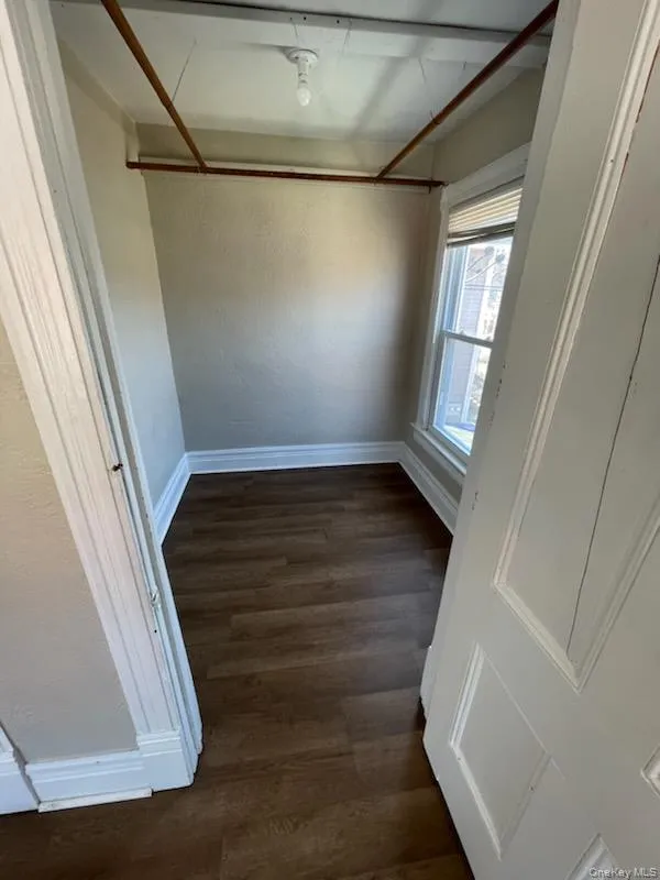Spare room with baseboards, dark wood-style floors, and a textured wall Spare room with baseboards, dark wood-style floors, and a textured wall