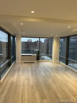 Empty room with a wall of windows, a city view, light wood finished floors, and recessed lighting Empty room with a wall of windows, a city view, light wood finished floors, and recessed lighting