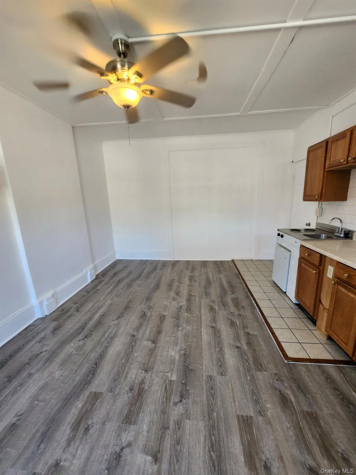 Kitchen featuring brown cabinets, ceiling fan, light countertops, and light wood-style flooring Kitchen featuring brown cabinets, ceiling fan, light countertops, and light wood-style flooring