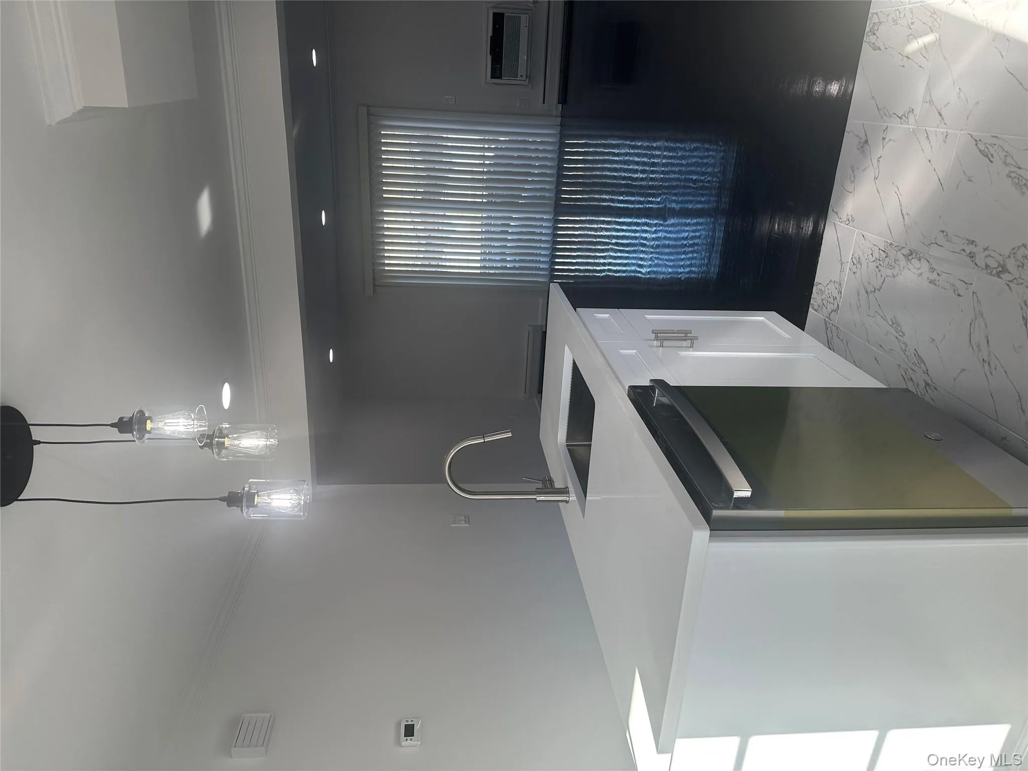 Kitchen featuring ornamental molding, light marble finish flooring, decorative light fixtures, dishwashing machine, and white cabinetry Kitchen featuring ornamental molding, light marble finish flooring, decorative light fixtures, dishwashing machine, and white cabinetry