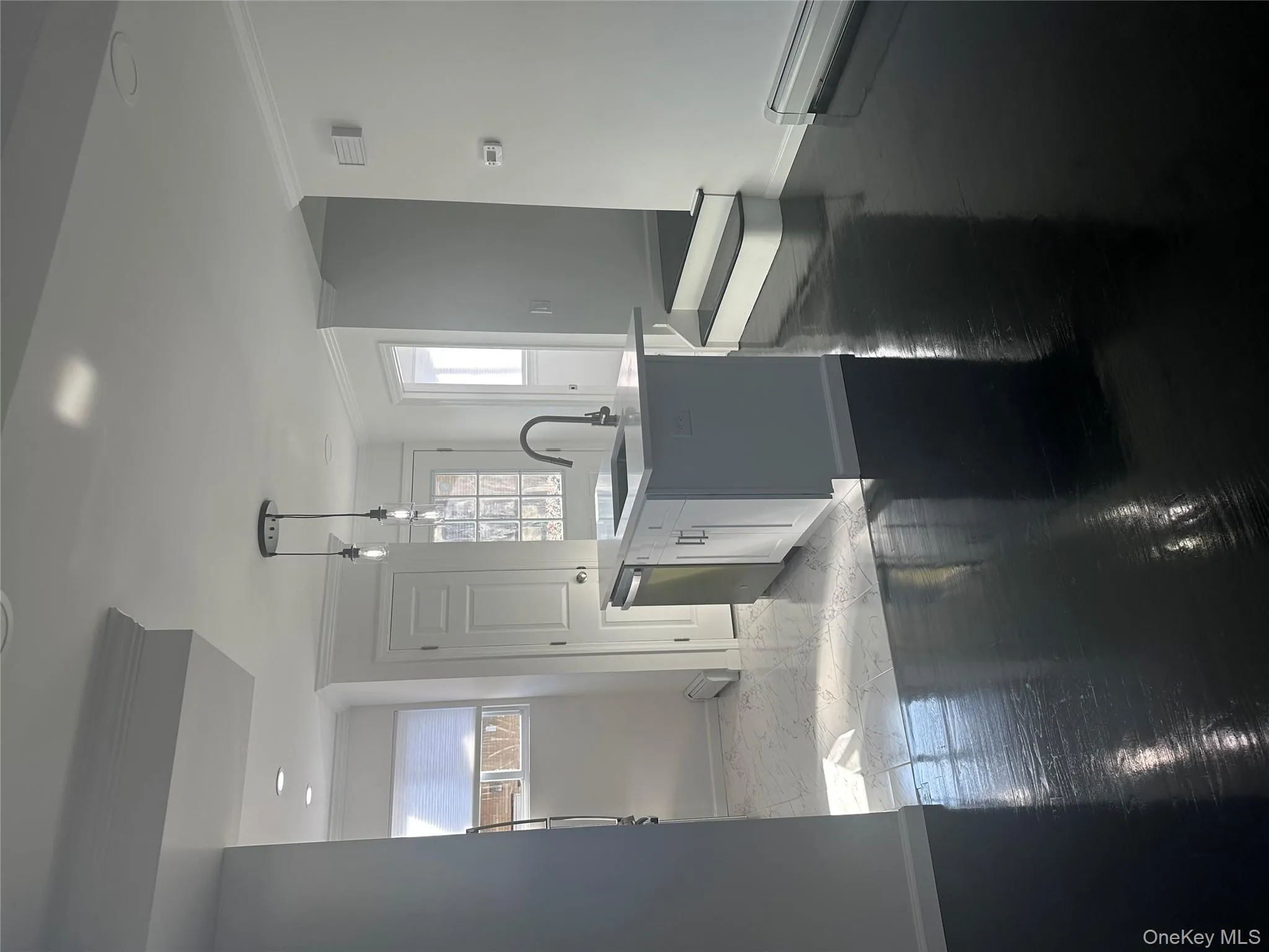 Kitchen featuring pendant lighting, an island with sink, crown molding, white cabinetry, and light stone countertops Kitchen featuring pendant lighting, an island with sink, crown molding, white cabinetry, and light stone countertops