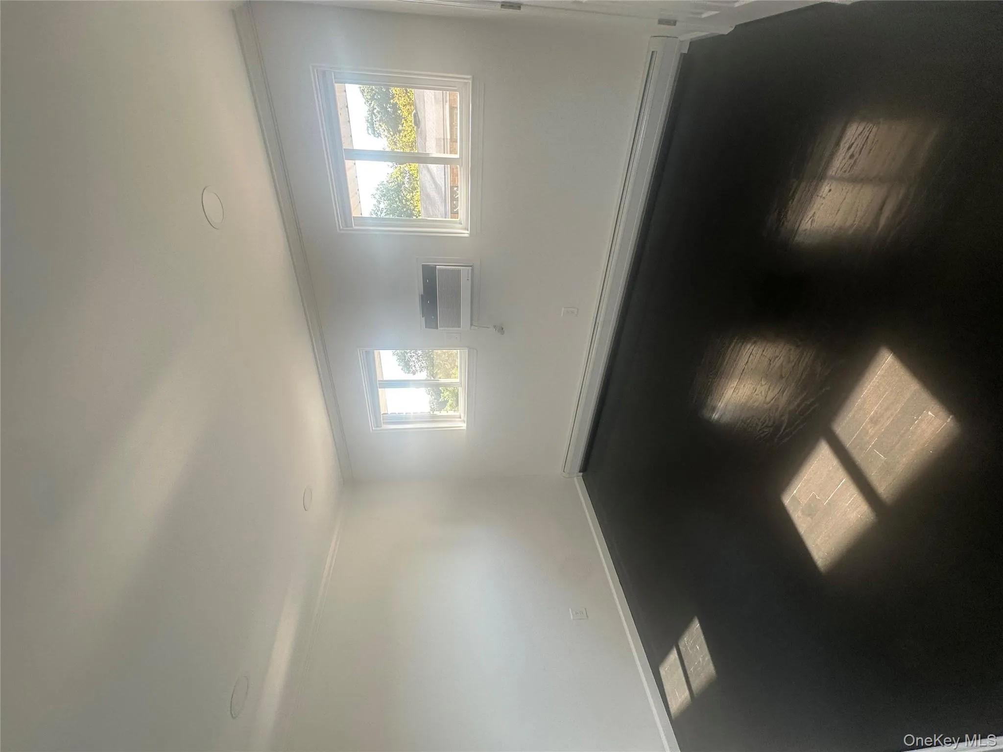 Unfurnished room with a baseboard heating unit, ornamental molding, wood finished floors, and a wall mounted air conditioner Unfurnished room with a baseboard heating unit, ornamental molding, wood finished floors, and a wall mounted air conditioner