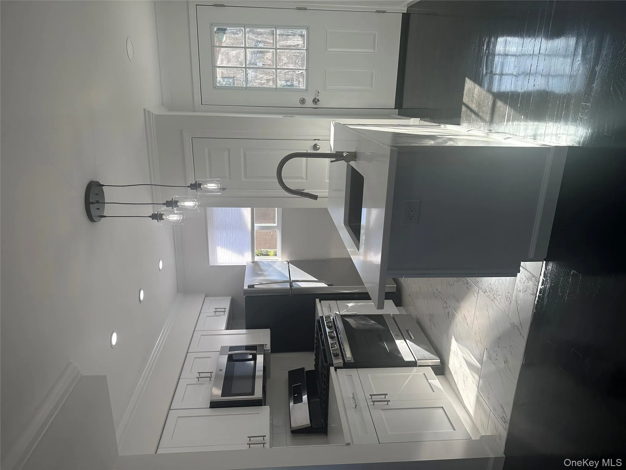 Kitchen featuring ornamental molding, stove, pendant lighting, white cabinetry, and a center island with sink Kitchen featuring ornamental molding, stove, pendant lighting, white cabinetry, and a center island with sink