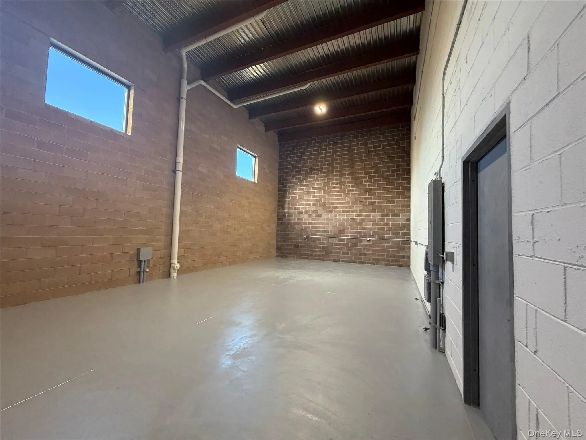 Miscellaneous room with finished concrete flooring, beamed ceiling, and a high ceiling Miscellaneous room with finished concrete flooring, beamed ceiling, and a high ceiling