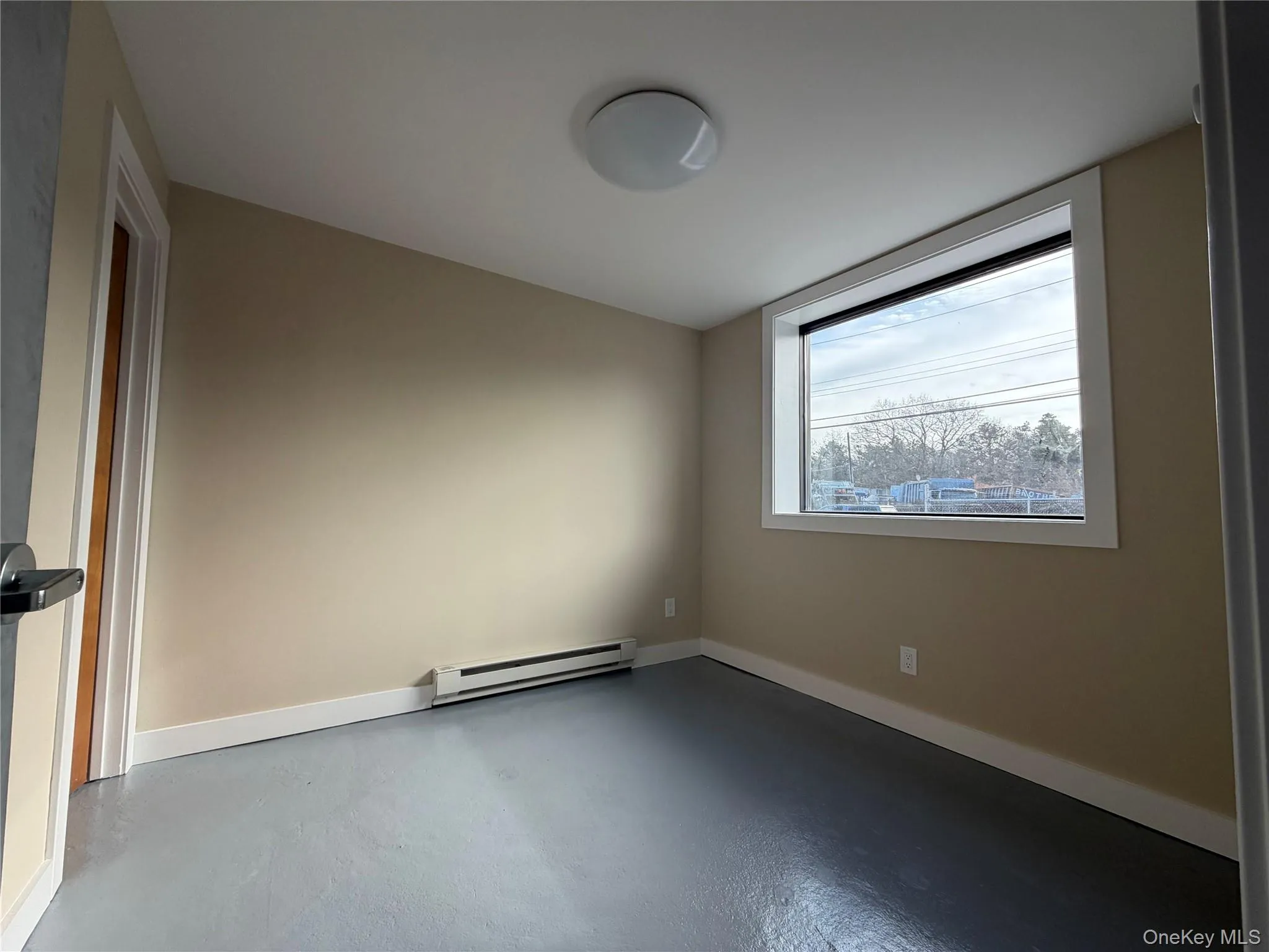 Empty room featuring finished concrete flooring and a baseboard heating unit Empty room featuring finished concrete flooring and a baseboard heating unit