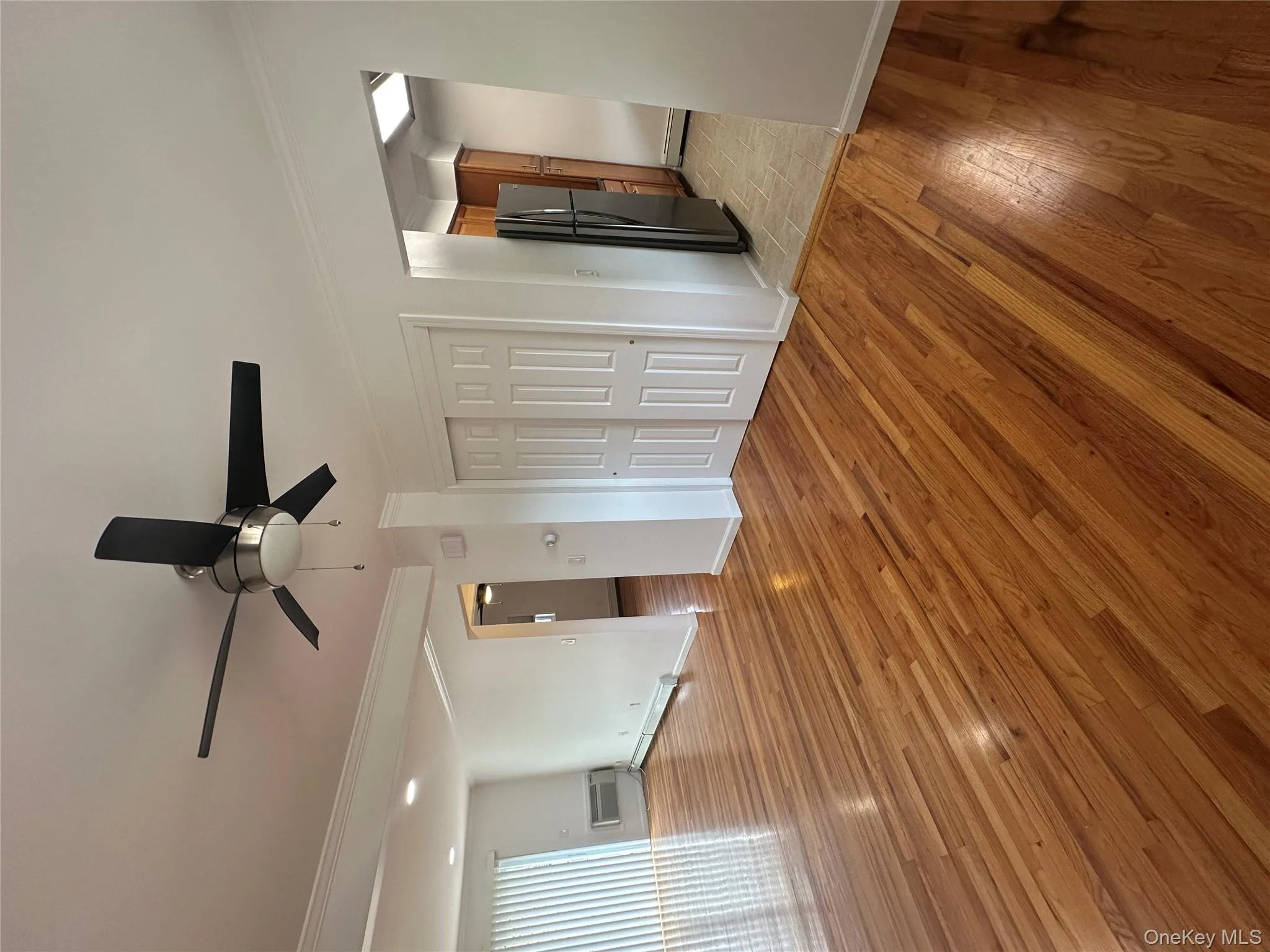 Unfurnished bedroom with light wood-style flooring, ornamental molding, refrigerator, ceiling fan, and a closet Unfurnished bedroom with light wood-style flooring, ornamental molding, refrigerator, ceiling fan, and a closet