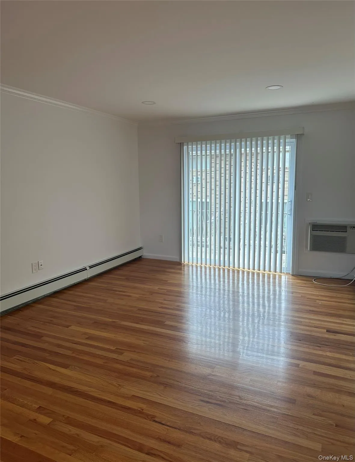 Unfurnished room with crown molding, wood finished floors, and a baseboard radiator Unfurnished room with crown molding, wood finished floors, and a baseboard radiator