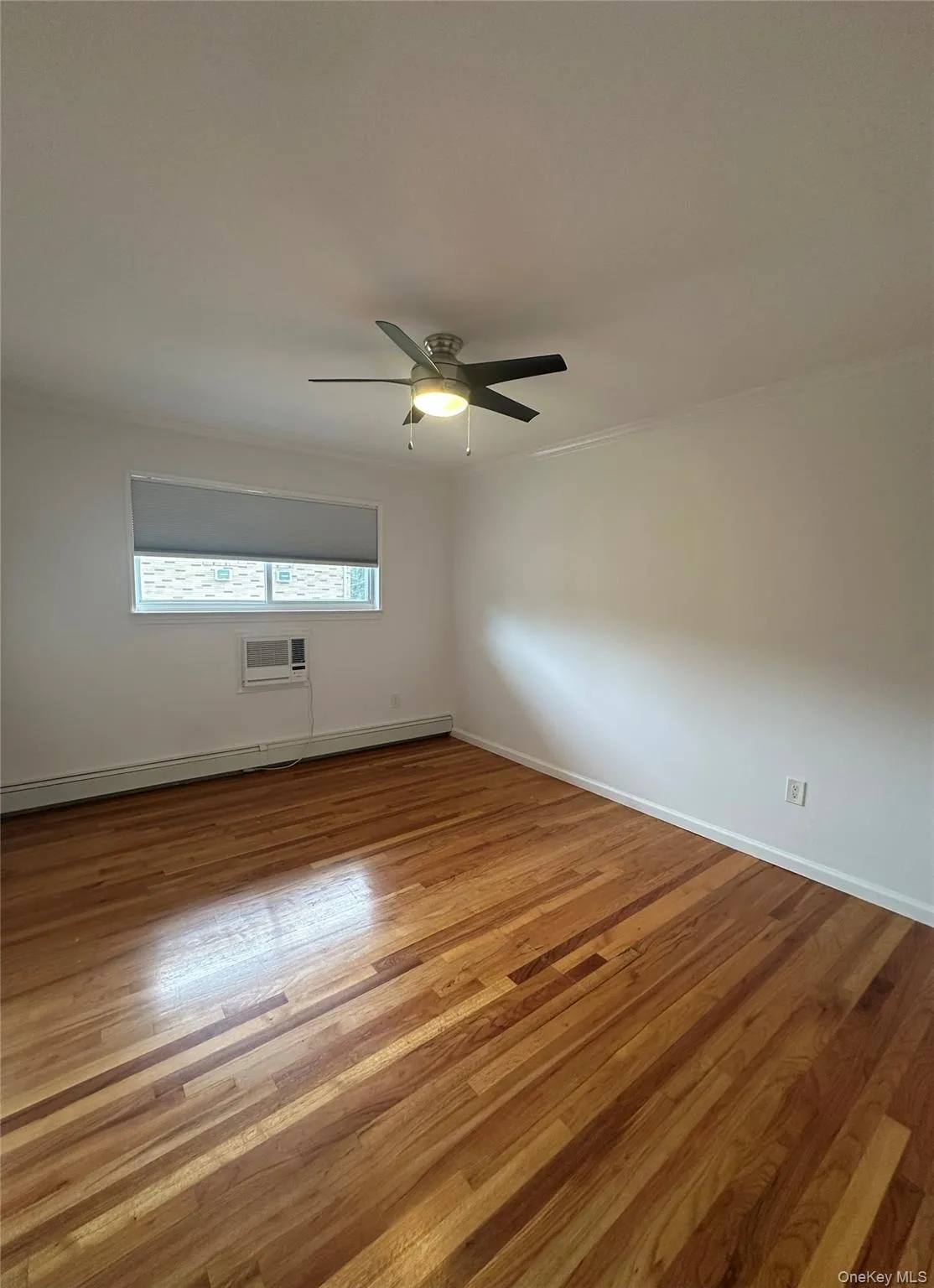 Unfurnished room with light wood-type flooring, baseboard heating, crown molding, and ceiling fan Unfurnished room with light wood-type flooring, baseboard heating, crown molding, and ceiling fan