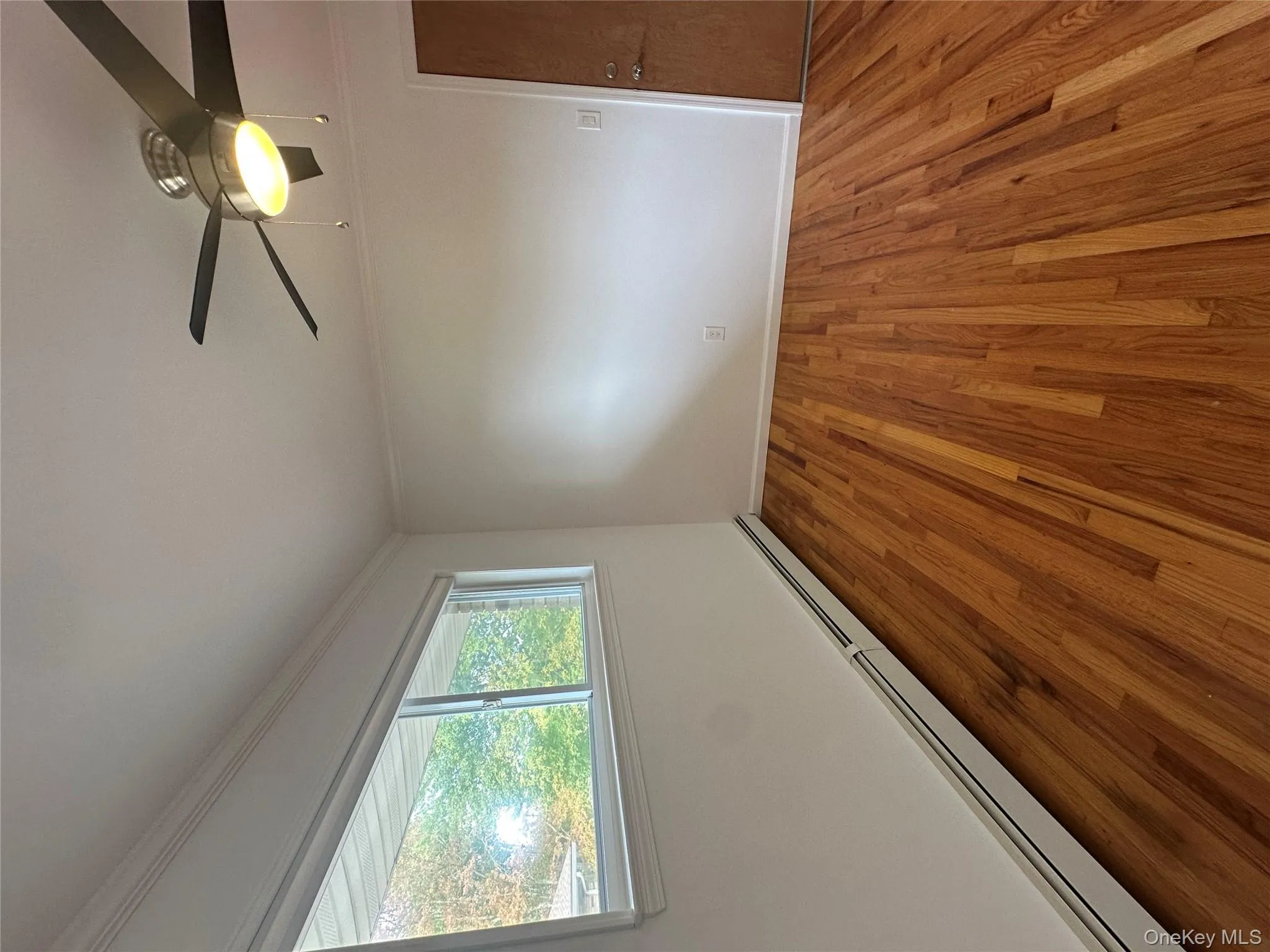 Unfurnished room featuring a baseboard heating unit, ornamental molding, wood finished floors, and a ceiling fan Unfurnished room featuring a baseboard heating unit, ornamental molding, wood finished floors, and a ceiling fan