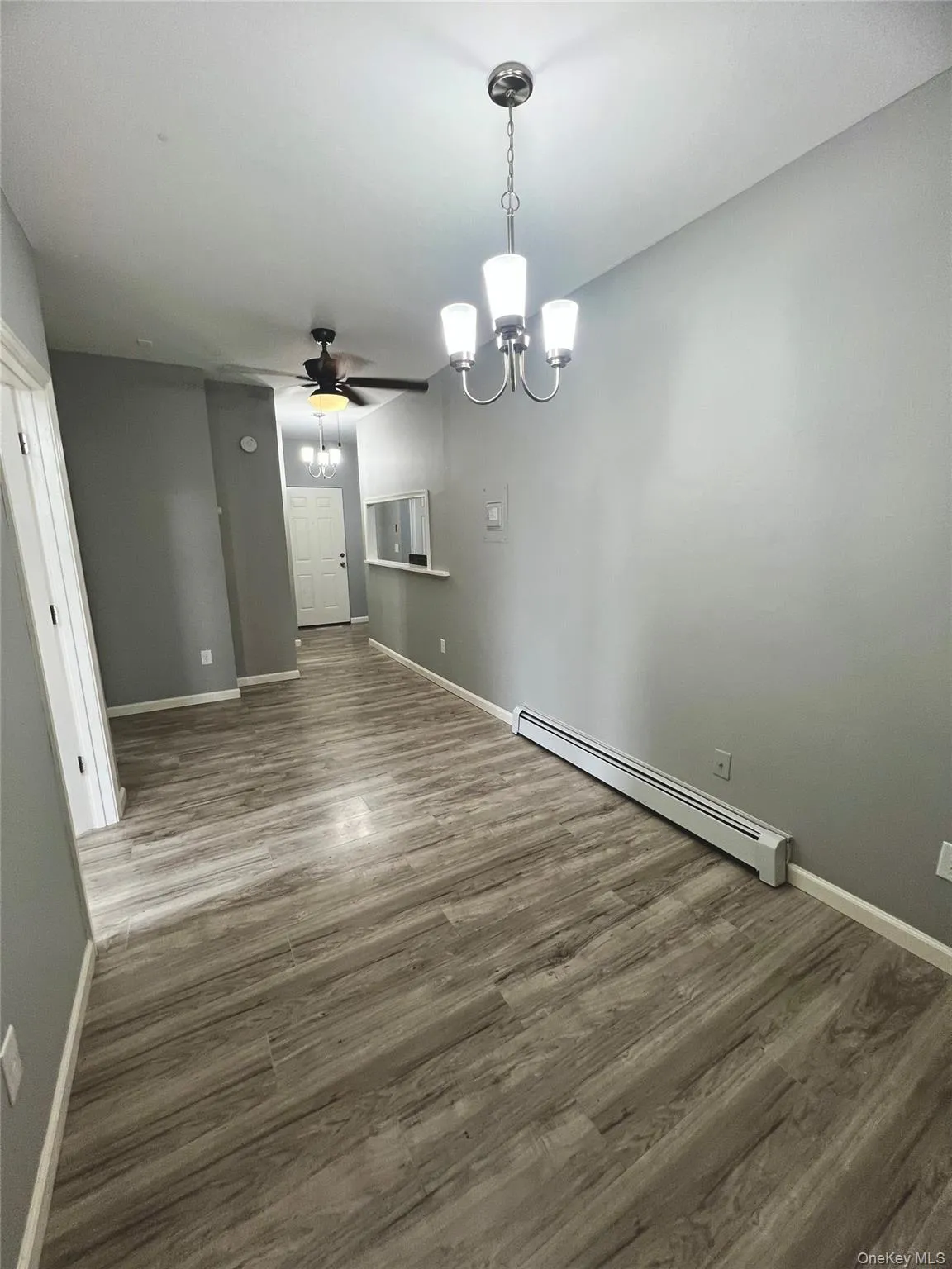 Unfurnished dining area with a baseboard radiator, a chandelier, wood finished floors, and a ceiling fan Unfurnished dining area with a baseboard radiator, a chandelier, wood finished floors, and a ceiling fan