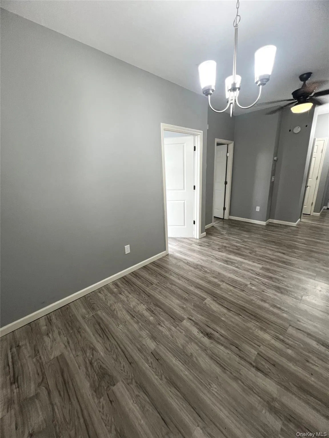 Unfurnished dining area with a chandelier, dark wood-style flooring, and ceiling fan Unfurnished dining area with a chandelier, dark wood-style flooring, and ceiling fan