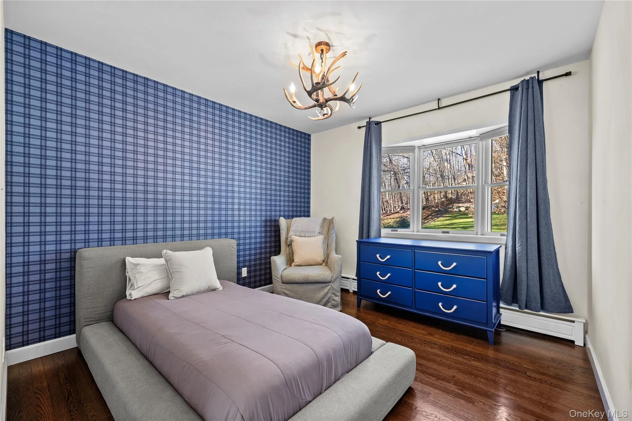 Bedroom featuring an accent wall, dark wood-style floors, wallpapered walls, baseboard heating, and a chandelier Bedroom featuring an accent wall, dark wood-style floors, wallpapered walls, baseboard heating, and a chandelier