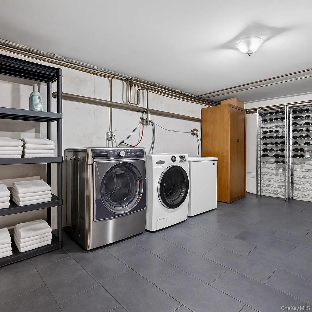 Washroom featuring washer and dryer and dark tile patterned floors Washroom featuring washer and dryer and dark tile patterned floors