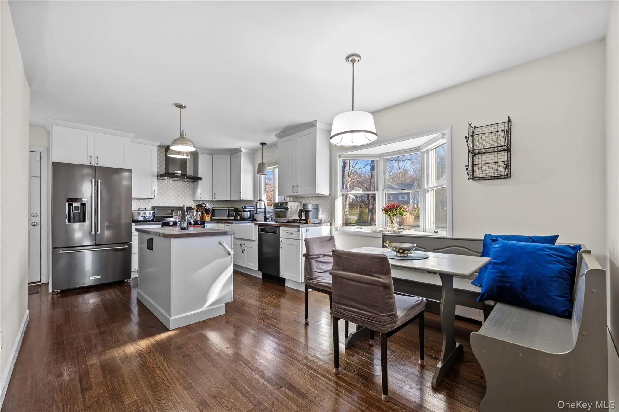 Kitchen with appliances with stainless steel finishes, hanging light fixtures, dark wood-type flooring, and dark countertops Kitchen with appliances with stainless steel finishes, hanging light fixtures, dark wood-type flooring, and dark countertops