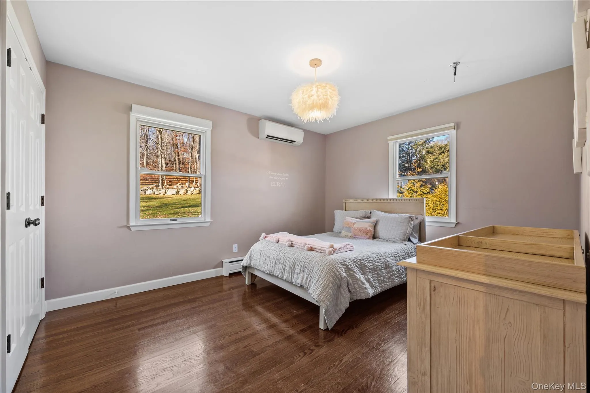 Bedroom with dark wood-style flooring, a closet, a wall mounted air conditioner, and a baseboard radiator Bedroom with dark wood-style flooring, a closet, a wall mounted air conditioner, and a baseboard radiator
