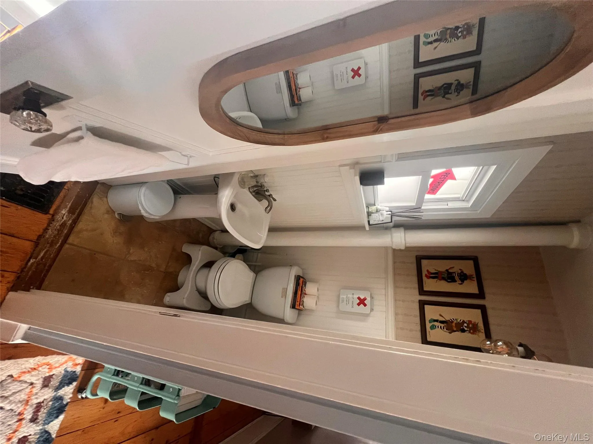 Half bathroom featuring wallpapered walls and a wainscoted wall Half bathroom featuring wallpapered walls and a wainscoted wall