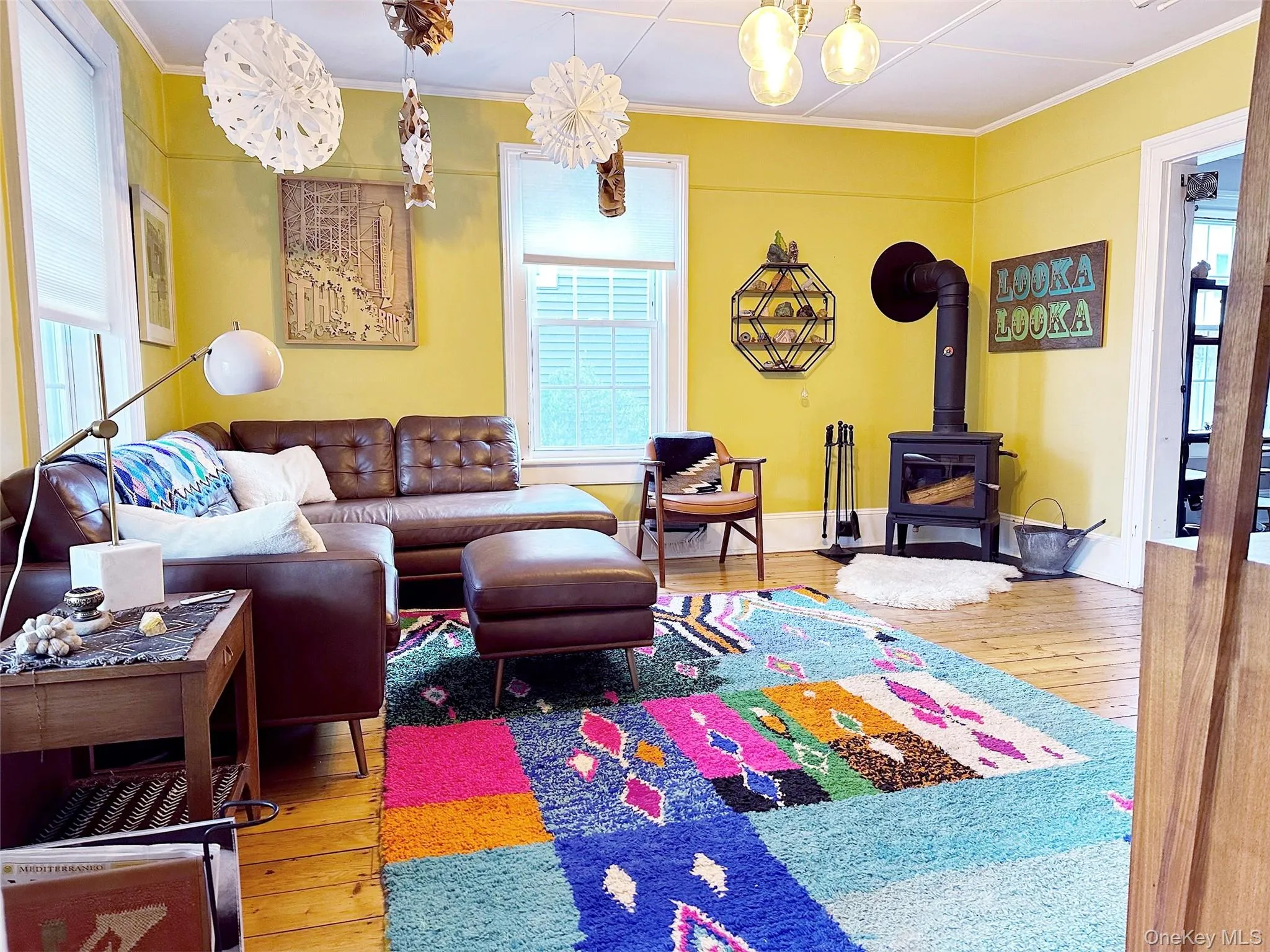 Living area featuring a wood stove, light wood finished floors, and crown molding Living area featuring a wood stove, light wood finished floors, and crown molding