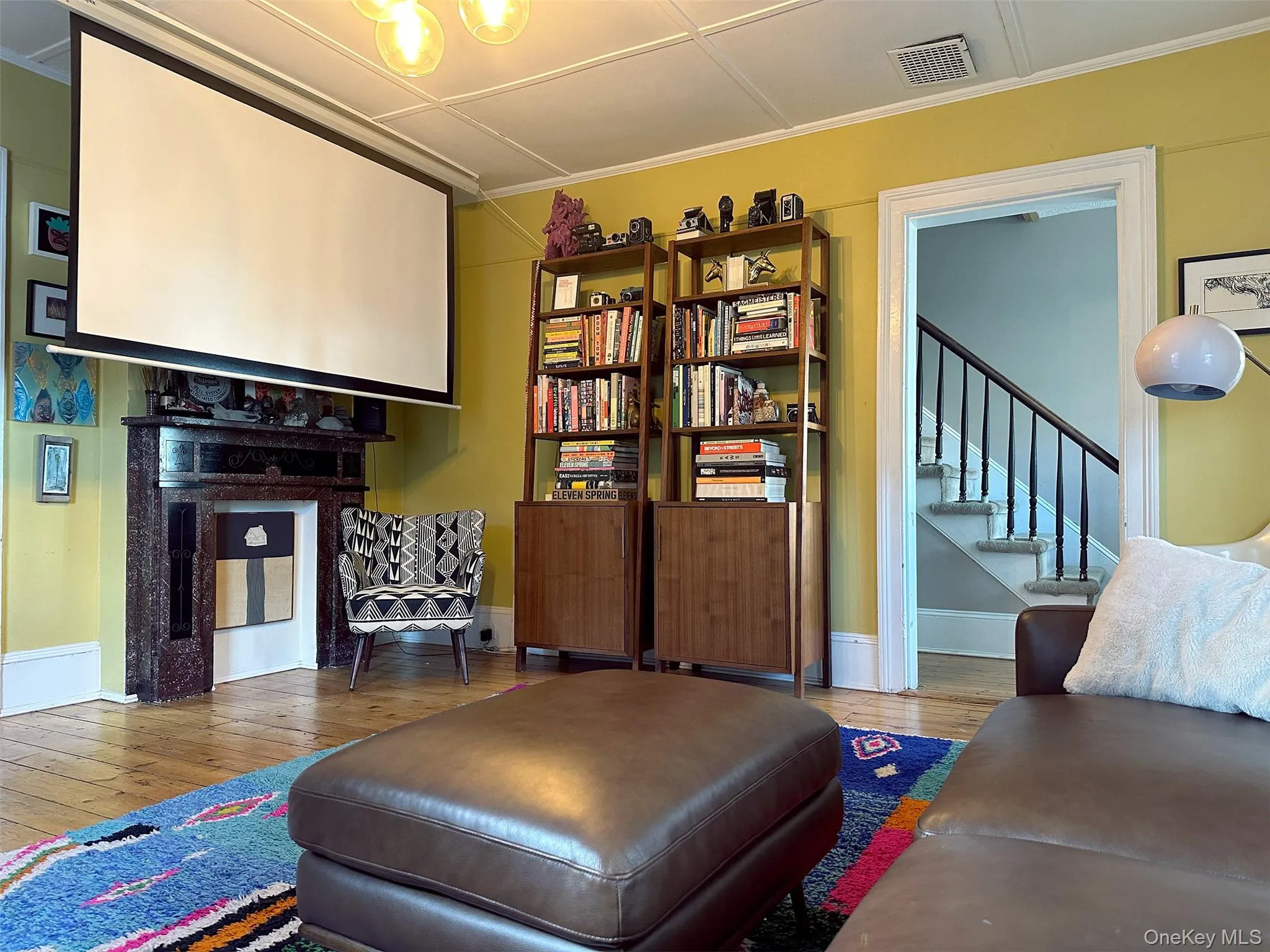 Sitting room featuring wood finished floors, ornamental molding, and stairs Sitting room featuring wood finished floors, ornamental molding, and stairs