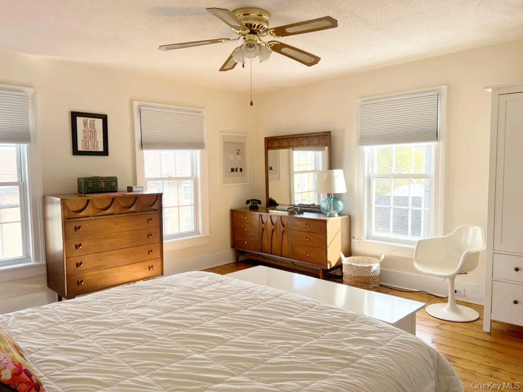 Bedroom with multiple windows, light wood-style floors, a textured ceiling, and a ceiling fan Bedroom with multiple windows, light wood-style floors, a textured ceiling, and a ceiling fan