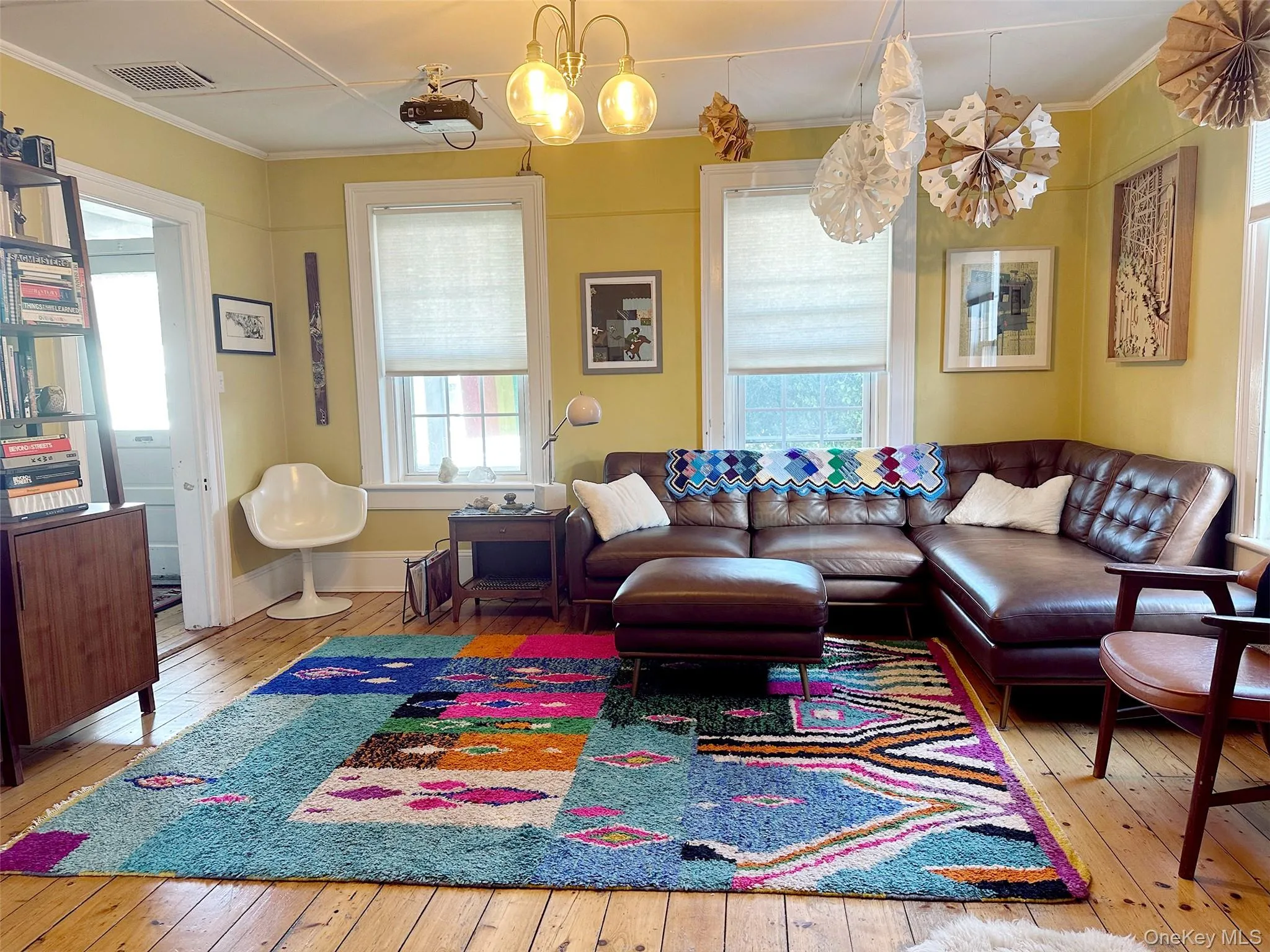 Living room featuring light wood-type flooring, a chandelier, and ornamental molding Living room featuring light wood-type flooring, a chandelier, and ornamental molding