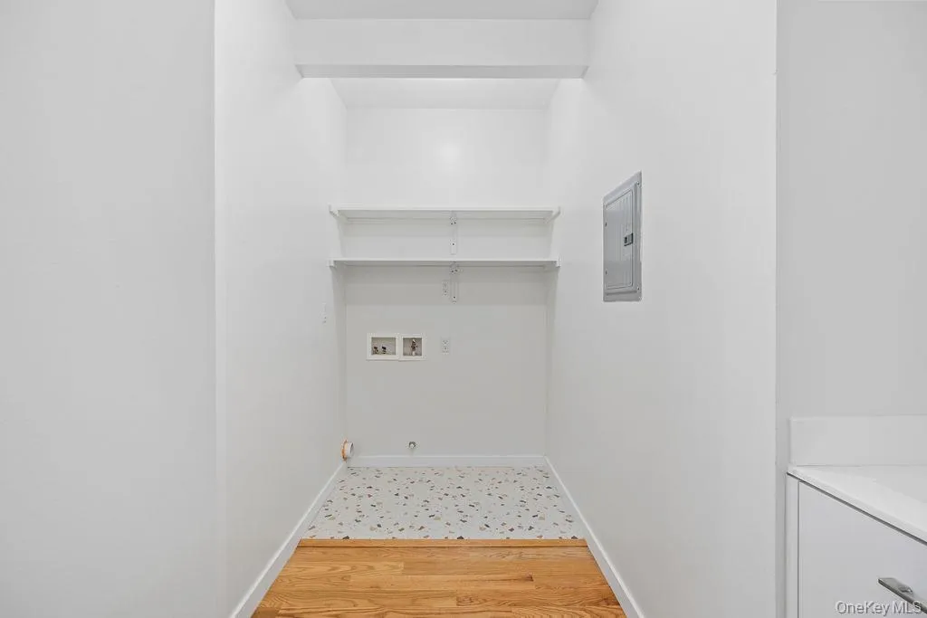 Laundry area featuring light wood-style flooring, washer hookup, and electric panel Laundry area featuring light wood-style flooring, washer hookup, and electric panel