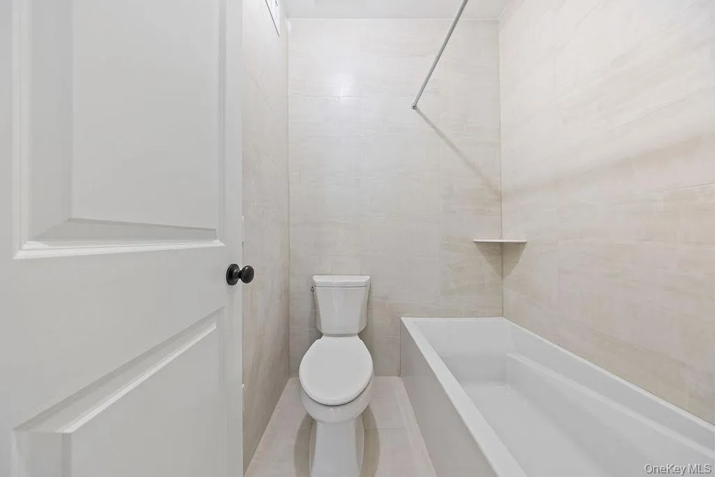 Full bathroom with tile walls, washtub / shower combination, and tile patterned floors Full bathroom with tile walls, washtub / shower combination, and tile patterned floors