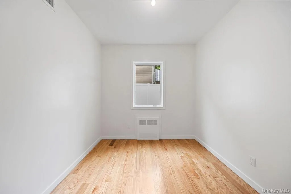 Spare room featuring light wood finished floors and radiator Spare room featuring light wood finished floors and radiator