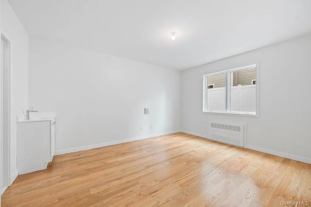 Unfurnished room featuring light wood-style flooring and radiator heating unit Unfurnished room featuring light wood-style flooring and radiator heating unit