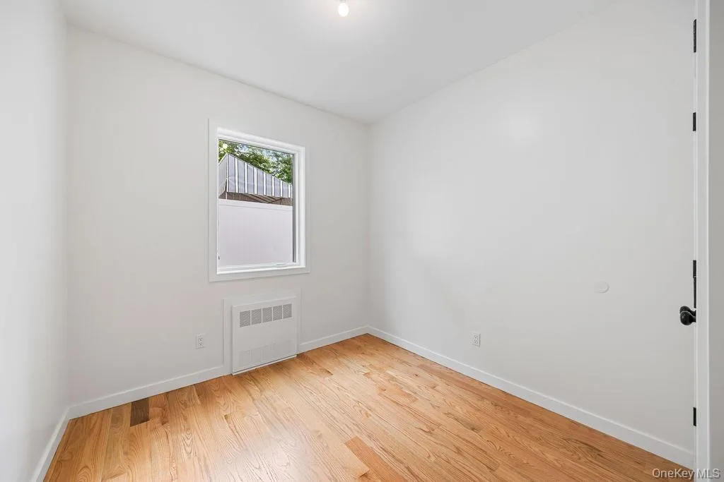 Empty room with radiator heating unit and light wood-style floors Empty room with radiator heating unit and light wood-style floors