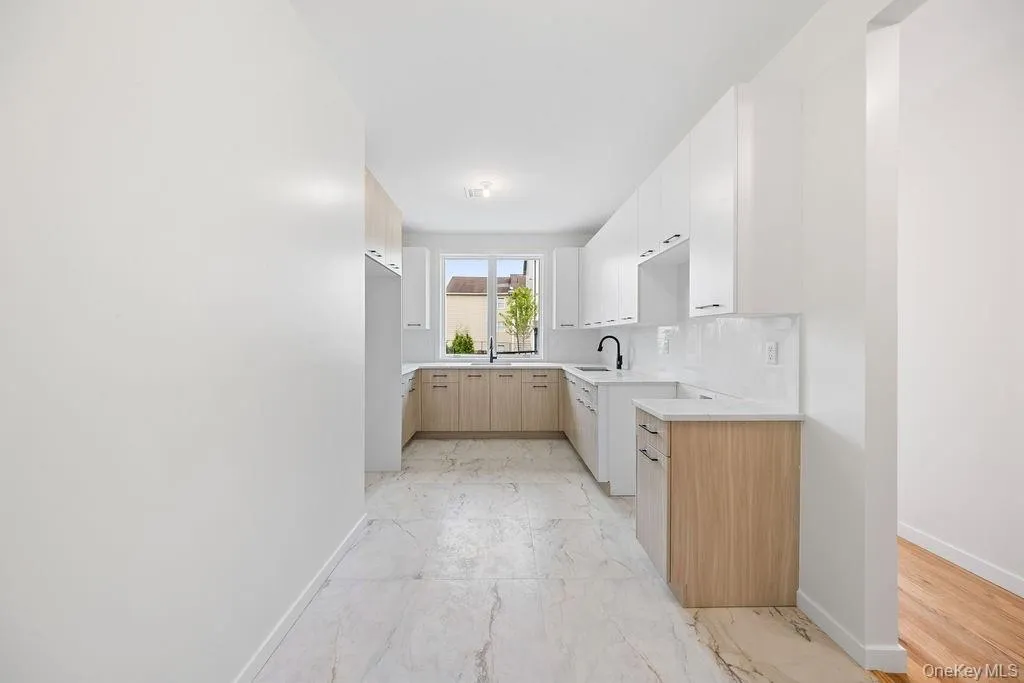 Kitchen with light brown cabinets, light marble finish floors, modern cabinets, decorative backsplash, and white cabinets Kitchen with light brown cabinets, light marble finish floors, modern cabinets, decorative backsplash, and white cabinets
