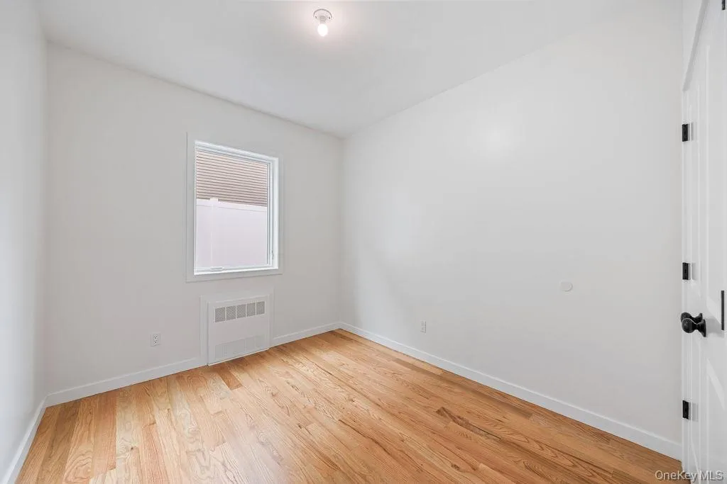 Unfurnished room featuring light wood-style flooring and radiator heating unit Unfurnished room featuring light wood-style flooring and radiator heating unit