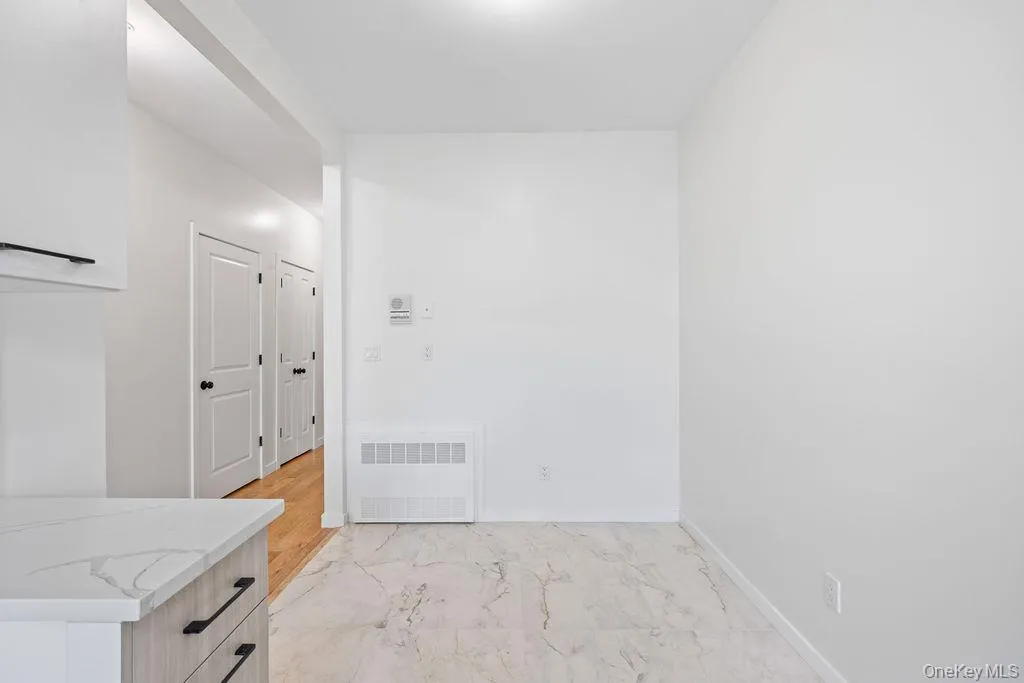 Unfurnished room featuring light marble finish floors and radiator heating unit Unfurnished room featuring light marble finish floors and radiator heating unit