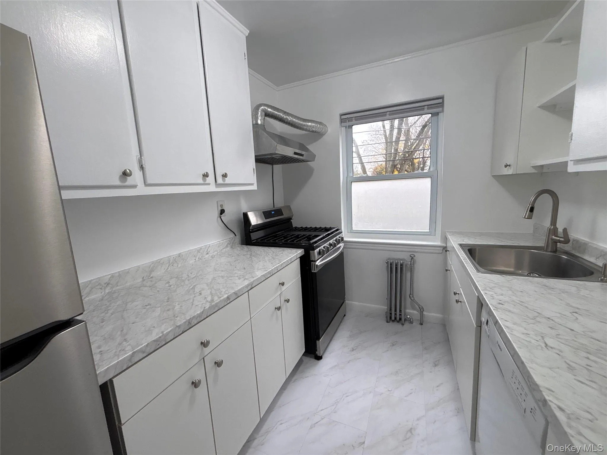 Kitchen featuring appliances with stainless steel finishes, light countertops, white cabinetry, open shelves, and crown molding Kitchen featuring appliances with stainless steel finishes, light countertops, white cabinetry, open shelves, and crown molding