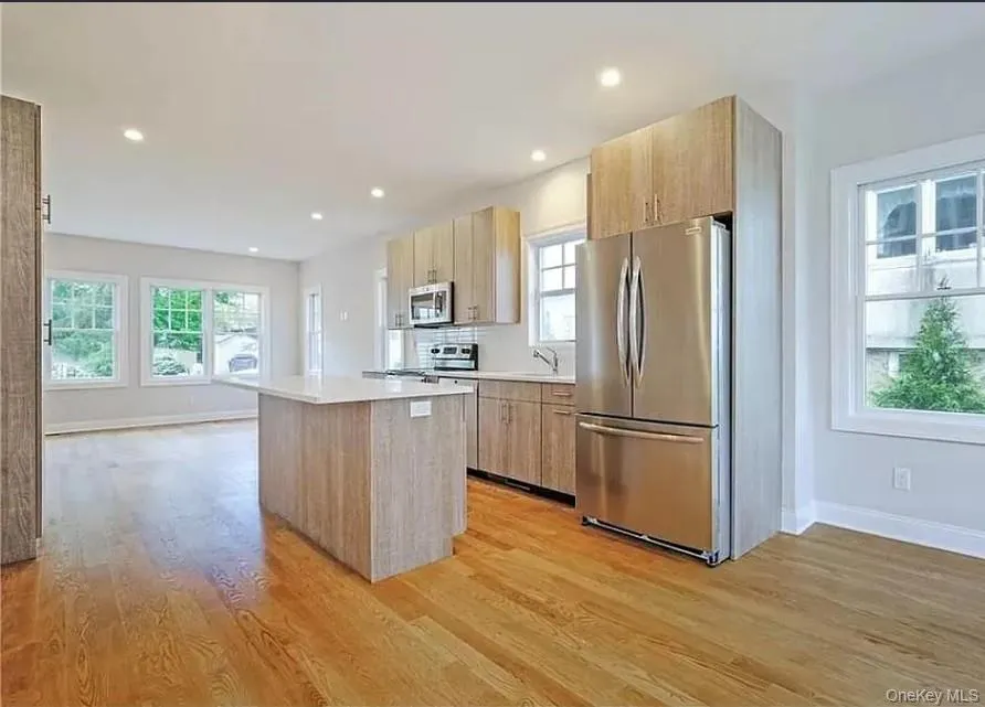 Kitchen with stainless steel appliances, light brown cabinetry, modern cabinets, a kitchen island, and light wood finished floors Kitchen with stainless steel appliances, light brown cabinetry, modern cabinets, a kitchen island, and light wood finished floors