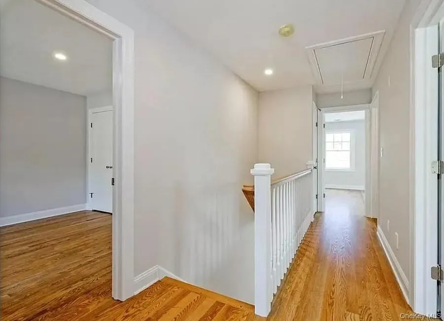 Corridor with attic access, light wood-style flooring, an upstairs landing, and recessed lighting Corridor with attic access, light wood-style flooring, an upstairs landing, and recessed lighting