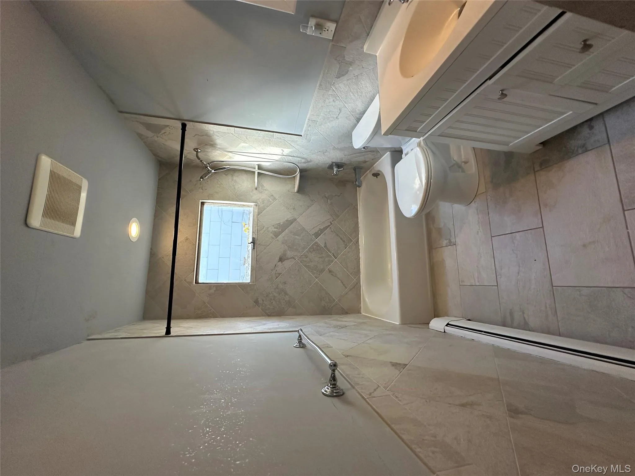 Full bathroom featuring tile walls, a baseboard radiator, vanity, wainscoting, and shower / bathtub combination Full bathroom featuring tile walls, a baseboard radiator, vanity, wainscoting, and shower / bathtub combination