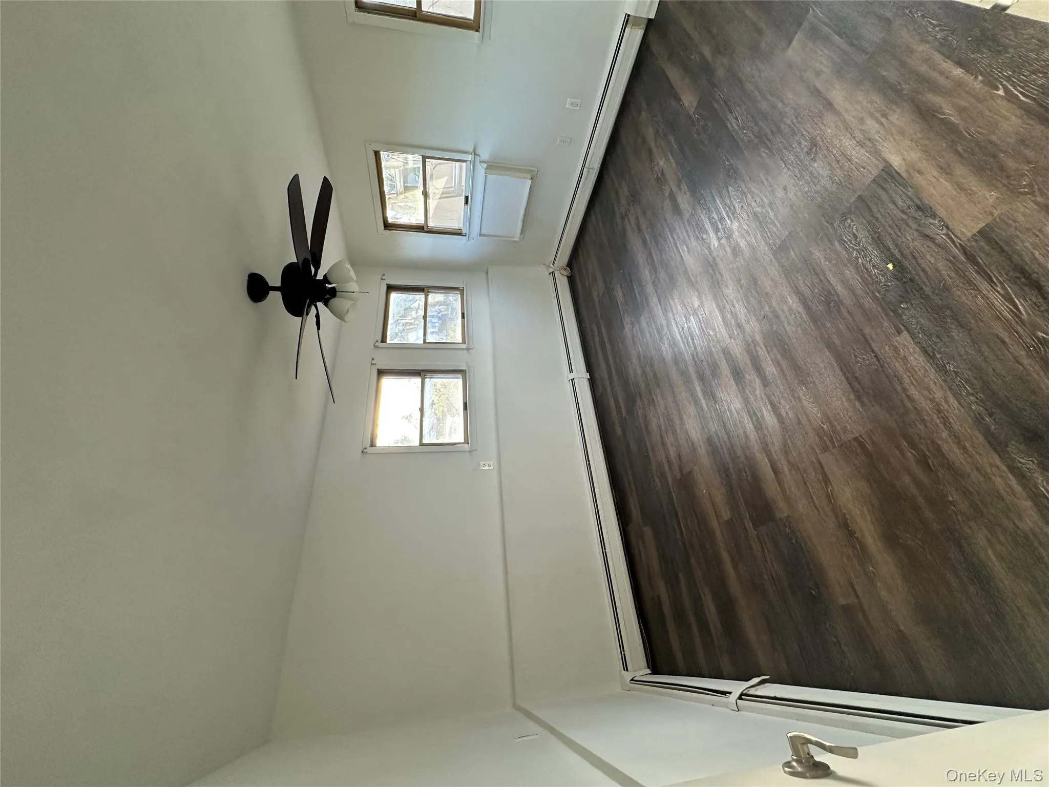 Unfurnished room with a baseboard heating unit, dark wood-style floors, and ceiling fan Unfurnished room with a baseboard heating unit, dark wood-style floors, and ceiling fan