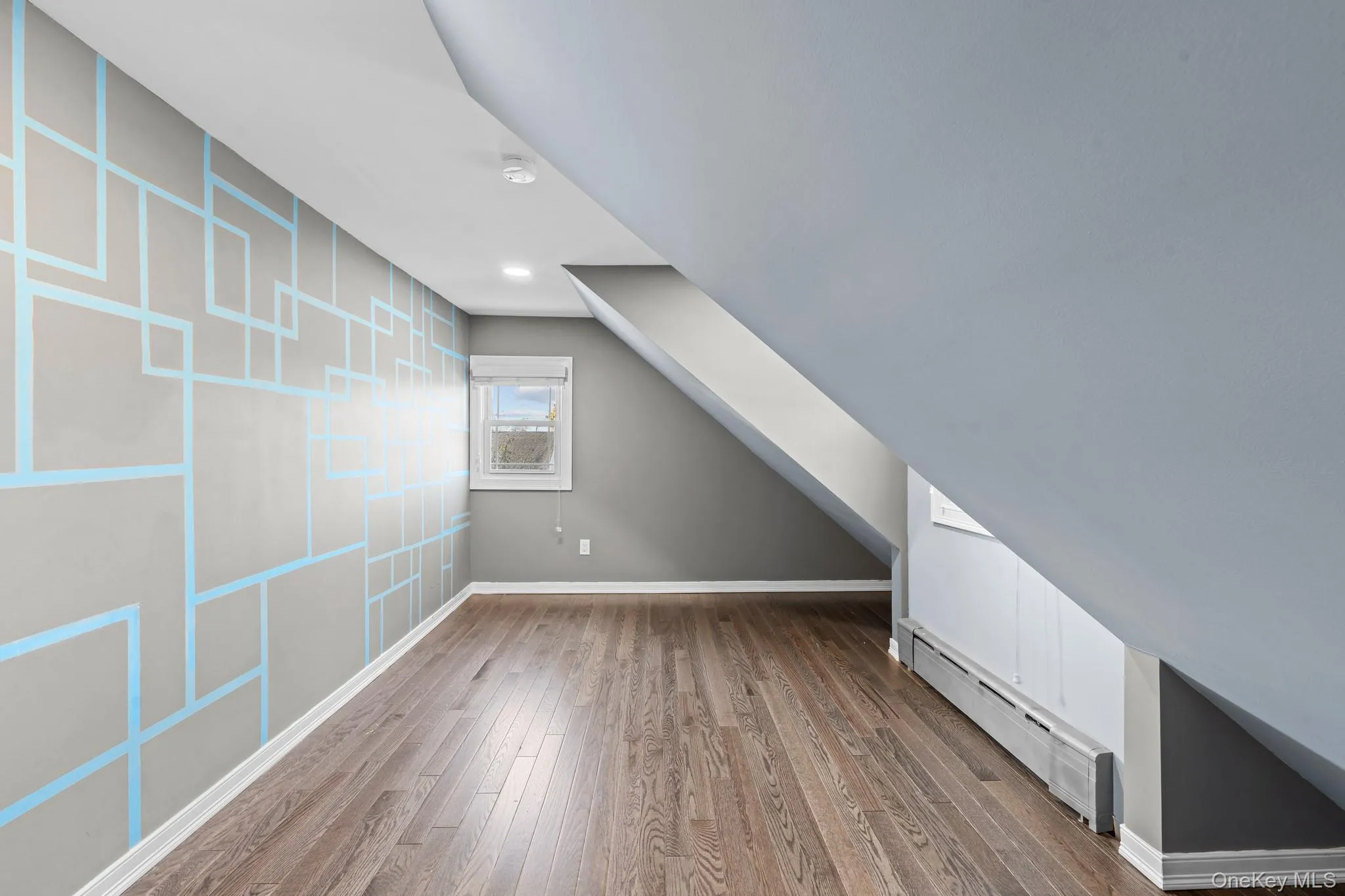 Additional living space featuring a baseboard heating unit and wood finished floors Additional living space featuring a baseboard heating unit and wood finished floors