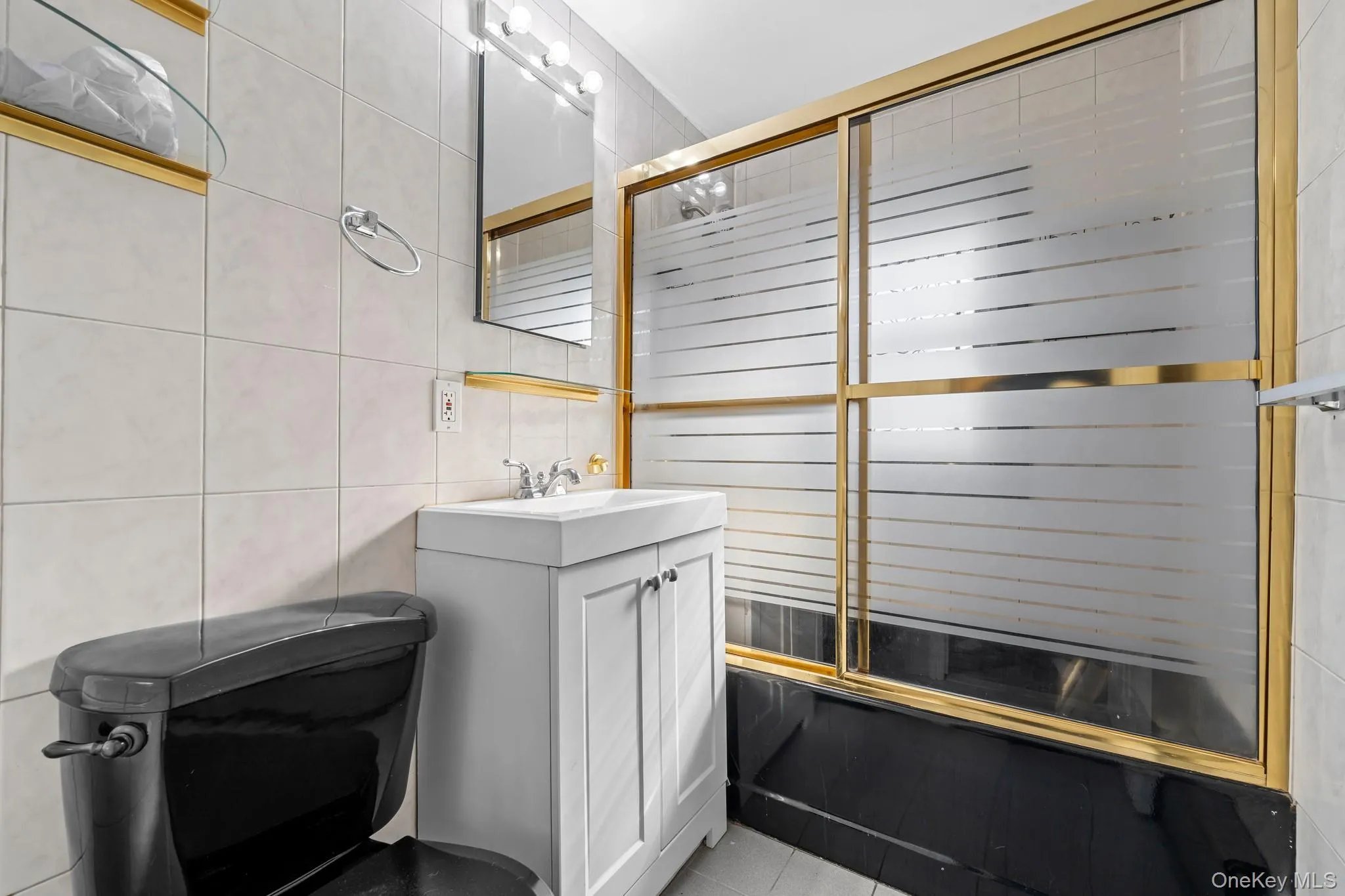 Bathroom featuring tile walls, vanity, a stall shower, and light tile patterned floors Bathroom featuring tile walls, vanity, a stall shower, and light tile patterned floors