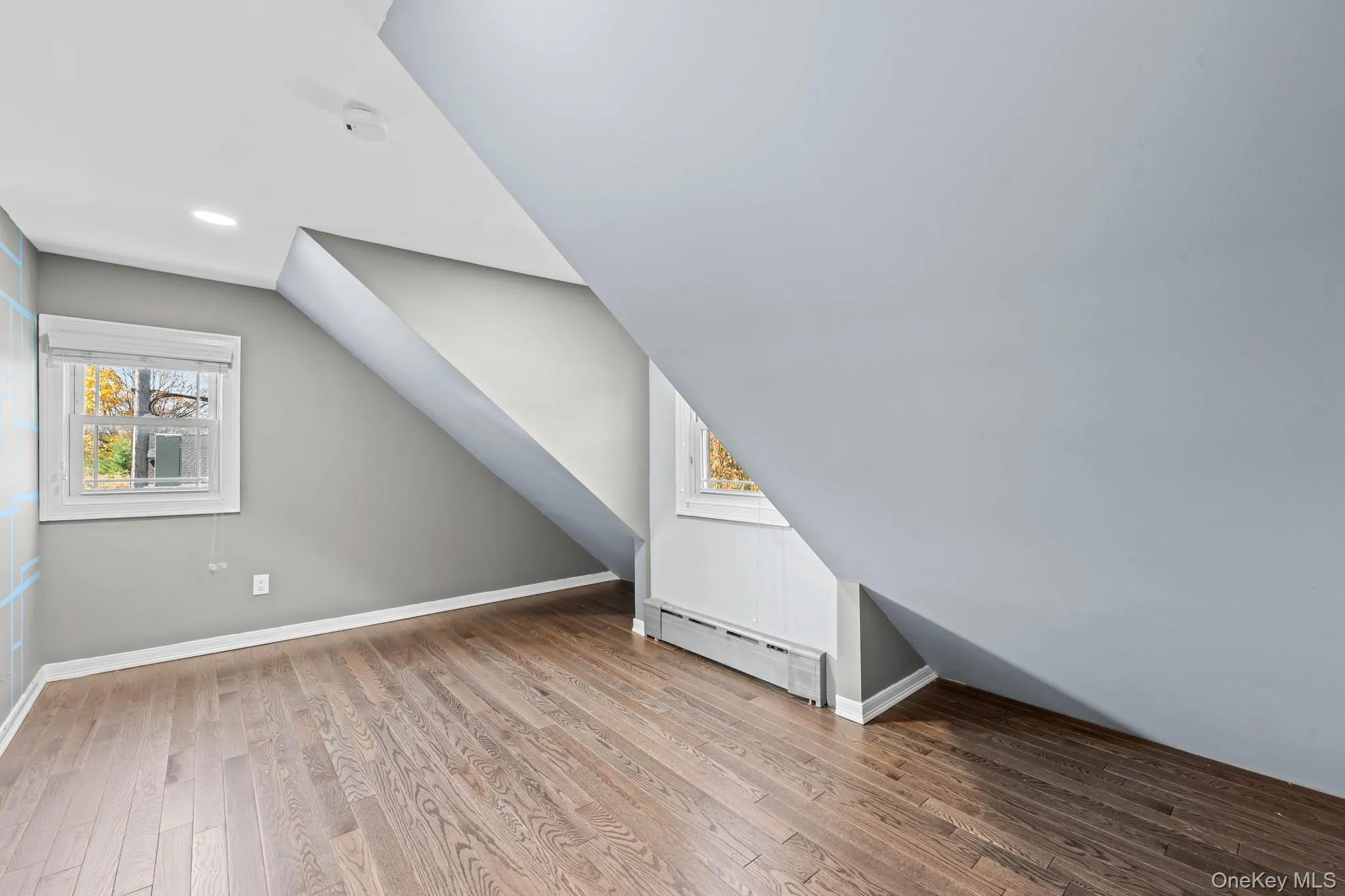 Additional living space featuring light wood finished floors, baseboard heating, lofted ceiling, and healthy amount of natural light Additional living space featuring light wood finished floors, baseboard heating, lofted ceiling, and healthy amount of natural light