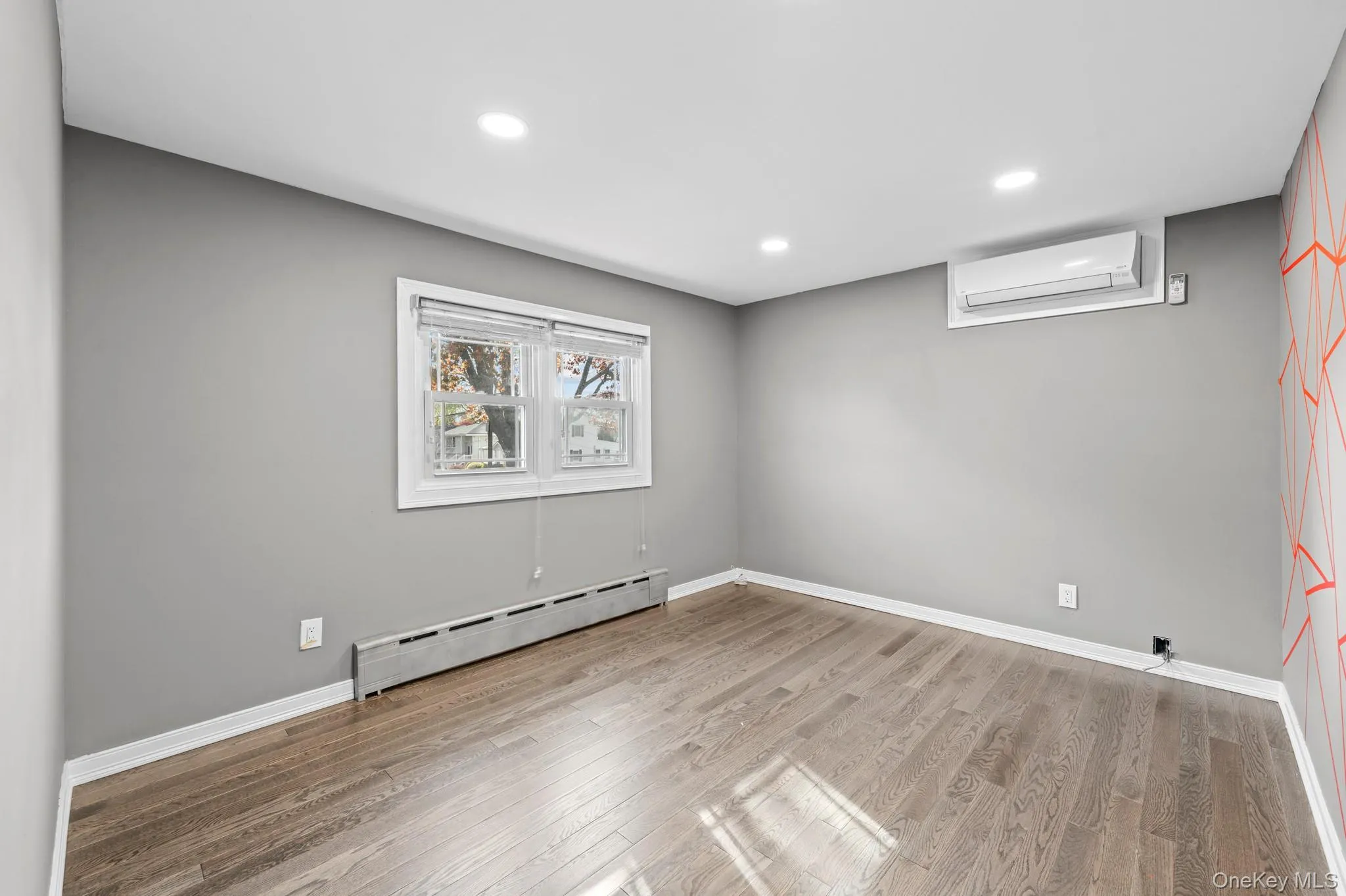 Basement featuring baseboard heating, light wood-style flooring, recessed lighting, and a wall mounted AC Basement featuring baseboard heating, light wood-style flooring, recessed lighting, and a wall mounted AC